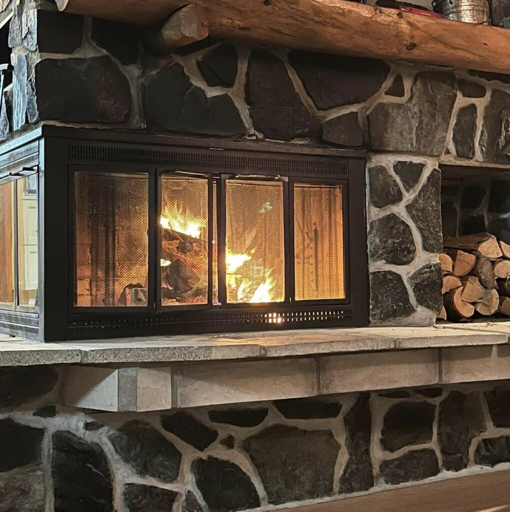 An indoor fireplace burning in a stone mantle