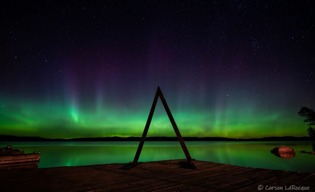Northernlights reflecting on a lake with an arch in the foreground